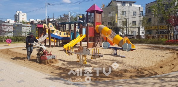 천안시 관계자가 어린이 모래놀이터의 소독을 위해 모래이물질제거 및 모래뒤집기를 하고 있다.