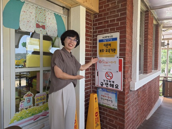 곽영주 제일어린이집 원장이 365x24 어린이집 현판 앞에서 기념사진을 찍고 있다.